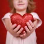 Child holding a heart in outstretched arms
